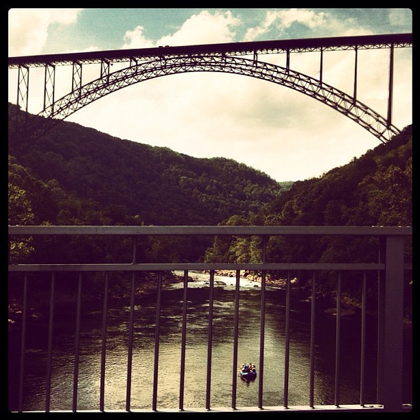 A raft floating beneath the New River Gorge Bridge on the New River in WV. #visitwv