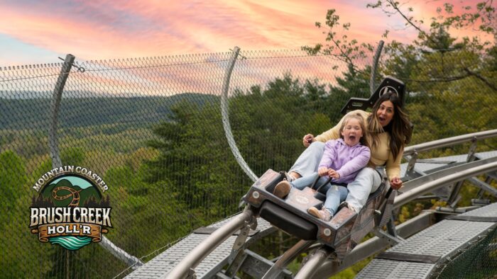 Mother and daughter looking excited on mountain coaster ride with the sunset in the background. Photo Credit: Brush Creek Holl'r Facebook