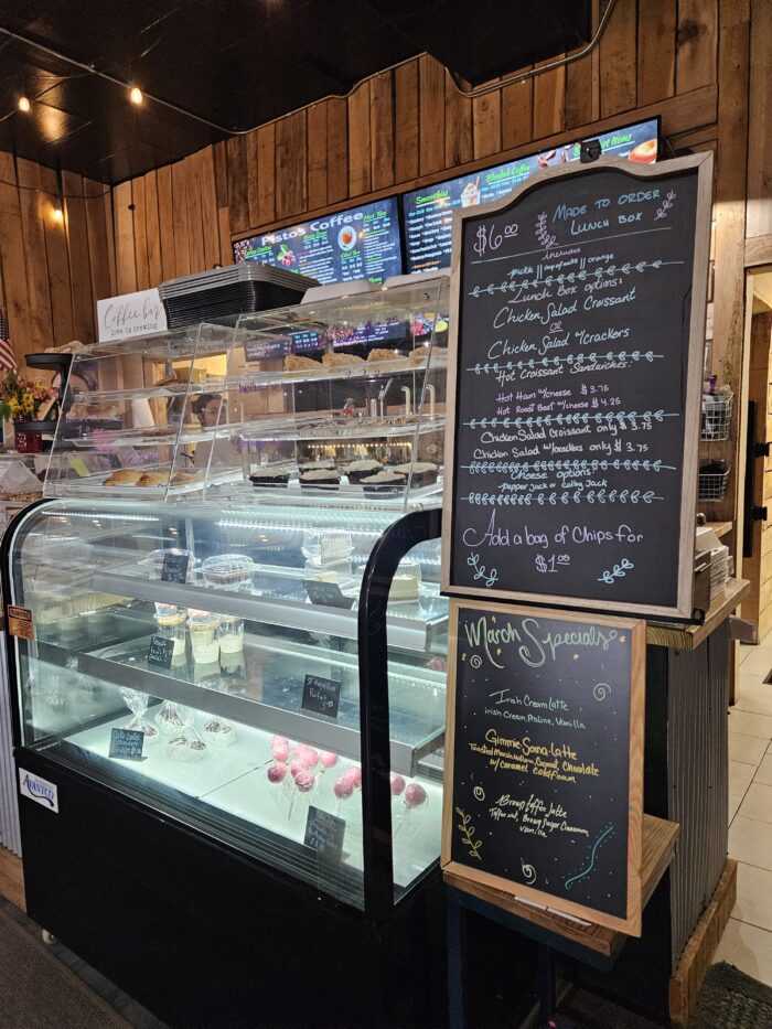 Bakery display case with desserts and chalkboard menu listing lunch box options and March specials.