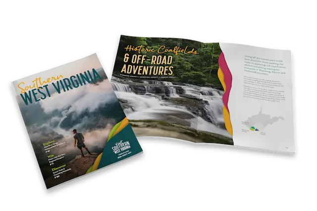 Tourism magazine showcasing Southern West Virginia, with a cover image of a lone hiker overlooking foggy mountain peaks. Inside, a vibrant two-page spread features a lush forest waterfall and information about off-road adventures and historic coalfields in Wyoming, McDowell, and Mercer counties.