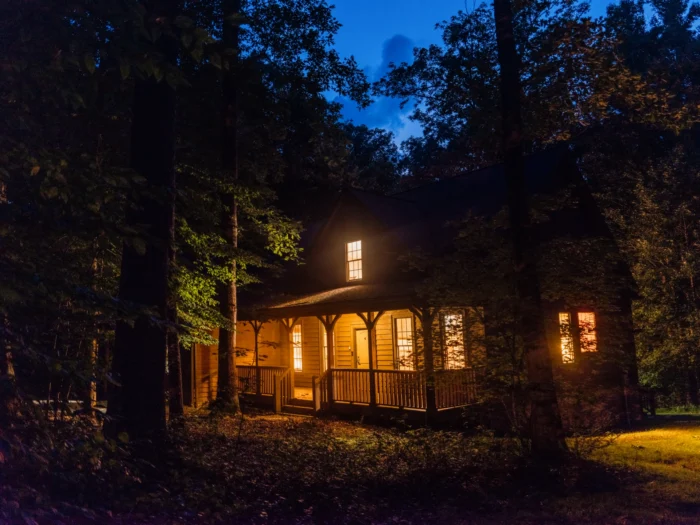 A cabin aglow at night in the forest
