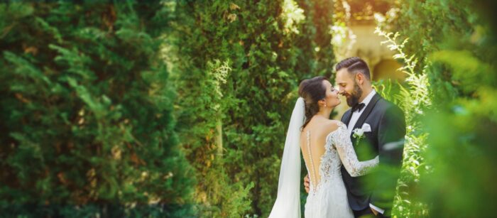 Bride and groom in the trees touching noses 