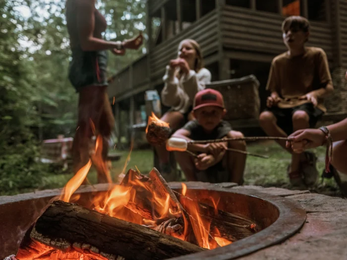 family gathered around a fire, roasting marshmellows